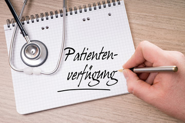 Schreibblock und Hand mit Stift schreibt Patientenverfügung