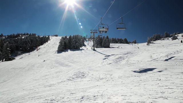 Ski Lift Moves Over The Snowy Mountain And The Sun Ray.
