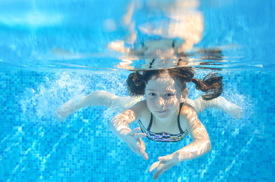 Happy active girl swims underwater in pool, kids sport