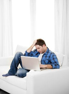 Worried Attractive man with computer sitting on couch