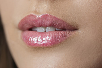 Close-up of woman's lips with bright natural pink glossy makeup