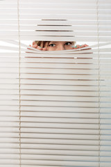 The woman looks through jalousie