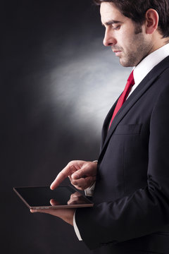 Businessman working on a digital tablet against black background