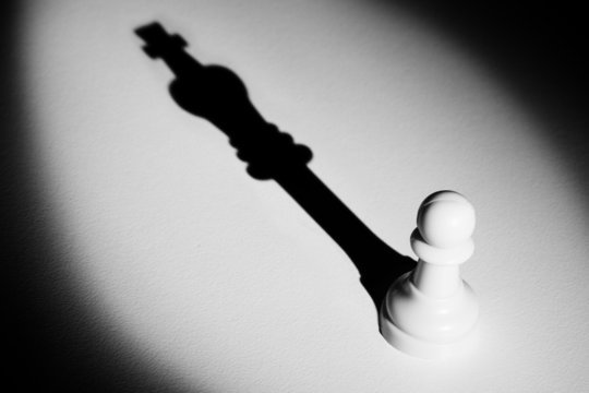 Chess pawn standing in a spotlight that make a shadow  actistic