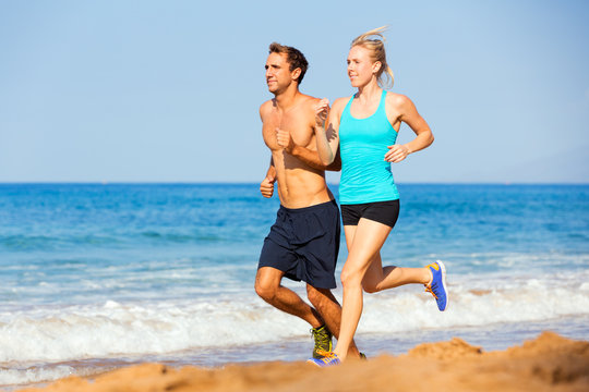 Sporty couple jogging together on the beach
