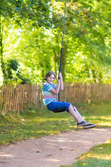 Fototapeta premium Cute school boy enjoying a swing ride on a playground