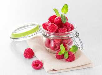 Fresh raspberries in a jar on the table close-up.