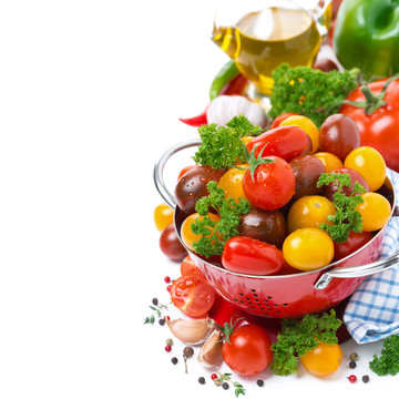 Assorted cherry tomatoes in a red colander, spices, olive oil