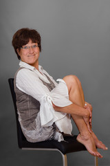 Full body portrait of a funny woman, sitting barefoot on a chair