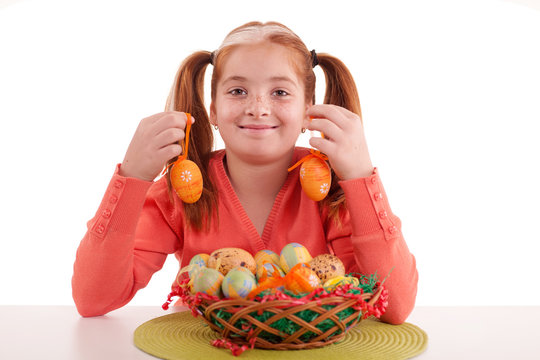 beautiful little red-haired girl with pigtails holding Easter eg