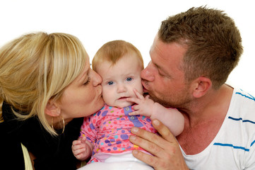 Mother and father are kissing baby