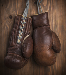 Old boxing gloves with a lace over old wooden wall