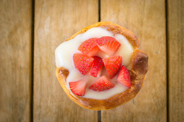Home  tart with strawberries and liquid custard on wooden table