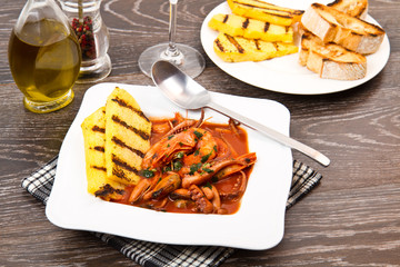 fish soup with grilled polenta on white dish
