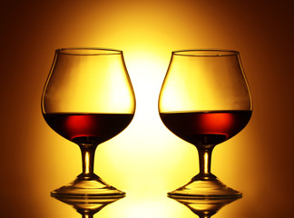 Two glasses of cognac on yellow background