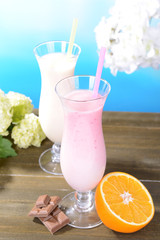 Milk shakes with fruits on table on light blue background