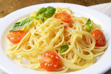 Delicious spaghetti with tomatoes on plate on table close-up