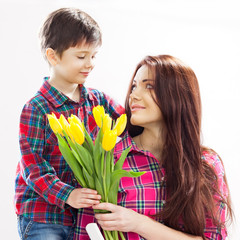 Son hugging his mother and gives her flowers