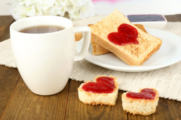 Delicious toast with jam and cup of tea on table close-up