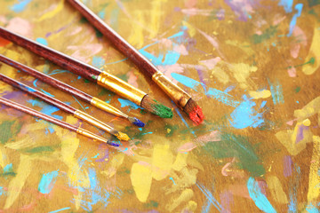 Obraz premium Many brushes in paints on multicolor wooden background