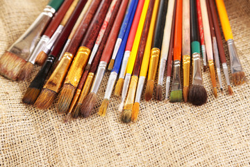 Fototapeta premium Many brushes in paints on sackcloth background