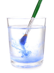 Brush with color paint in glass of water, isolated on white