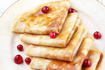 Pancakes with cranberry berries and honey on a plate