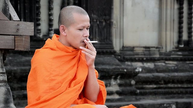 cambodian monk smoking in angkor wat temple