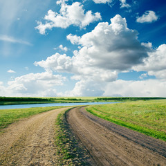 Fototapeta na wymiar rural road in green grass and cloudy sky
