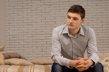 Young man sitting on a sofa thinking