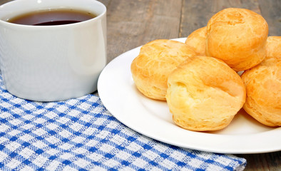 profiteroles and a cup of tea on a wooden table
