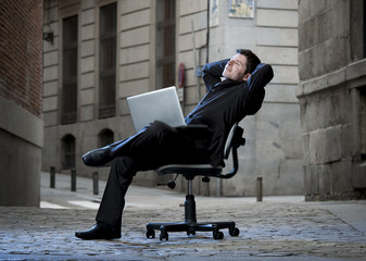 Happy Business Man sitting on Office Chair on Street with laptop
