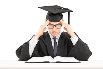 Student in graduation gown trying to concentrate on studying