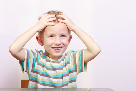 Portrait of surprised emotional blond boy child kid at the table