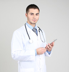 Male Doctor standing with folder, on gray background