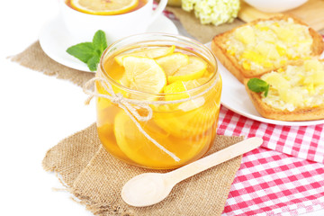 Tasty lemon jam with cup of tea on table close-up