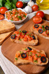 Delicious bruschetta with tomatoes on cutting board close-up