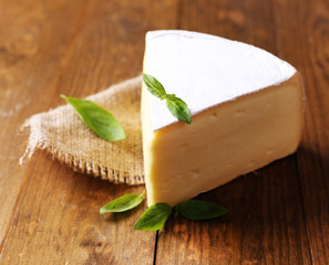 Tasty Camembert cheese with basil, on wooden table