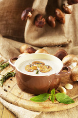 Mushroom soup in pot, on napkin,  on wooden background