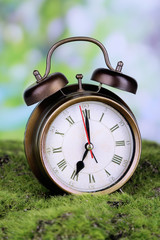 Retro alarm clock on grass on natural background