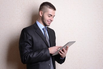 Portrait of businessman with tablet near wall
