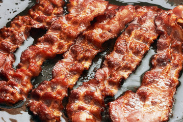 Bacon slice being cooked in frying pan