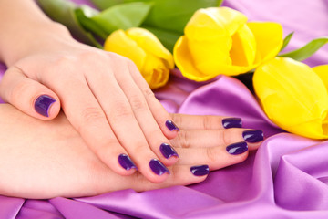 Fototapeta premium Beautiful woman hands with flowers on fabric background