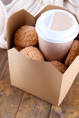 Hot coffee and cookies in box on wooden table close-up