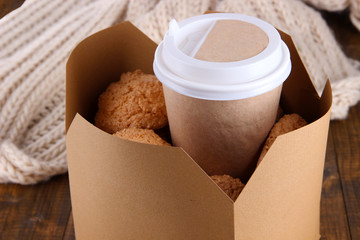 Hot coffee and cookies in box on wooden table close-up