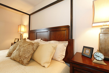 High posts bed with a beautiful beige bedding and nightstand. Cl