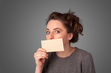 Cute girl holding white card at front of her lips with copy spac