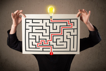 Businessman holding a paper with a labyrinth on it in front of h