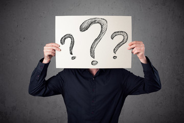 Businessman holding a paper with question marks in front of his