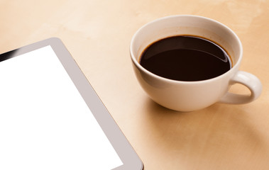 Tablet pc with empty space and a cup of coffee on a desk
